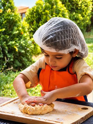 Criança de touca preparando uma receita na cozinha