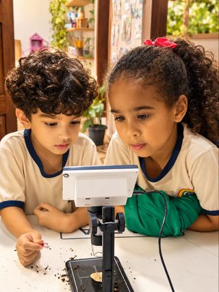 Crianças observando pequenas descobertas com um microscópio na sala de aula
